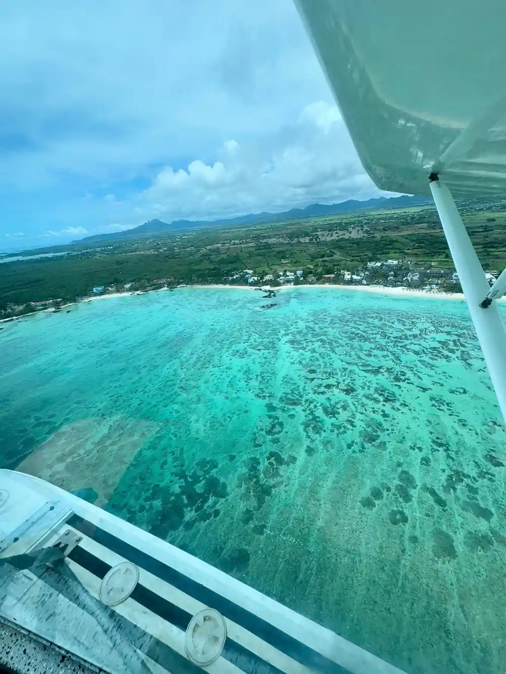 A coastline and green ridge past the float, clear shallows below