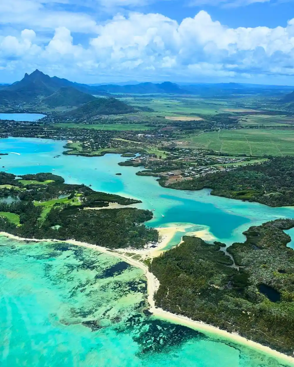 Green lowland with lagoon inlets and a distant peak