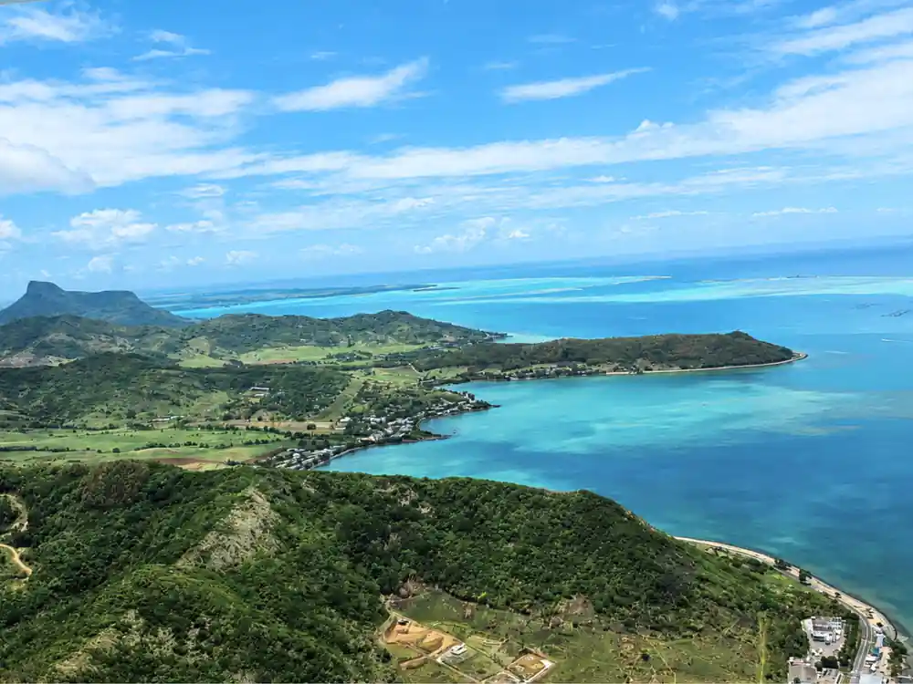 A green ridge and bay from altitude with the reef line beyond