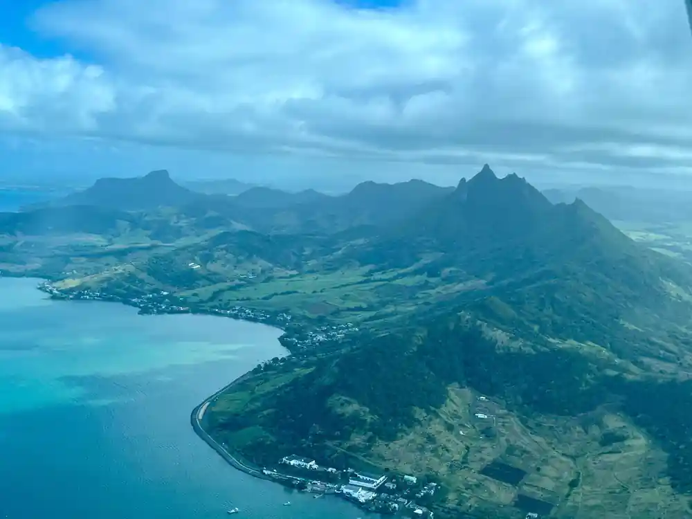 A long green coast and mountain range meeting a pale lagoon