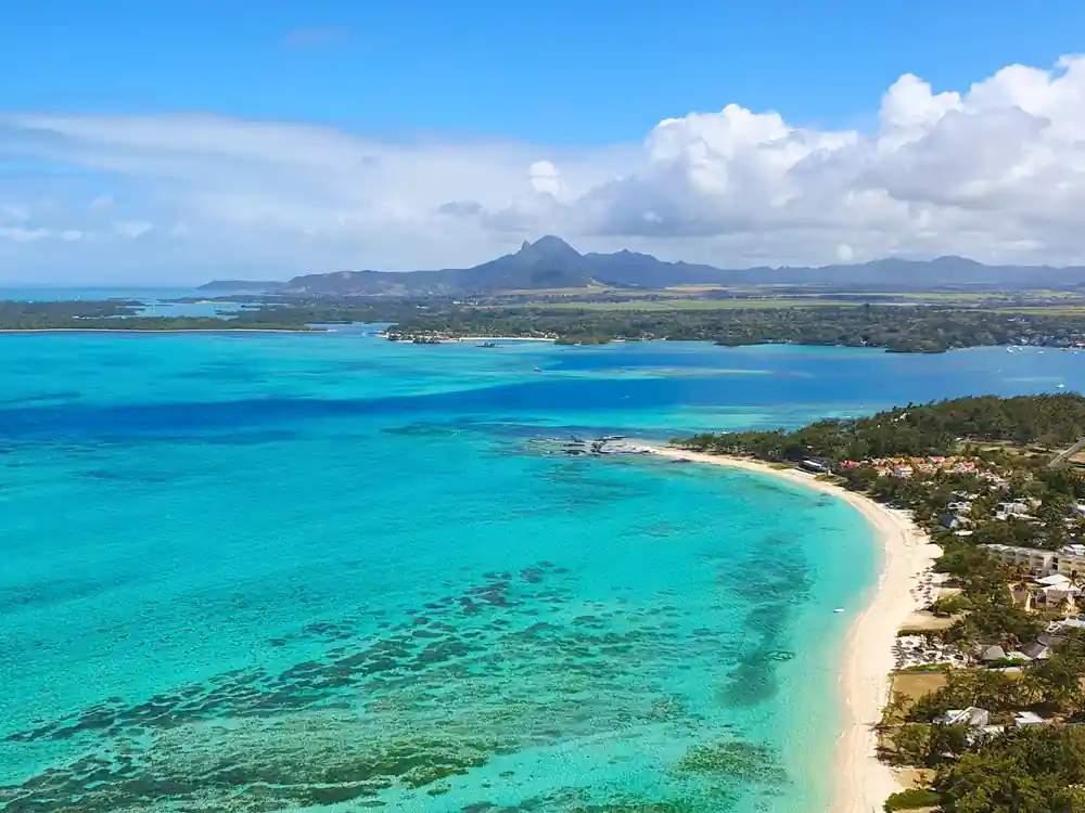 A long white beach curving to a headland with mountains behind