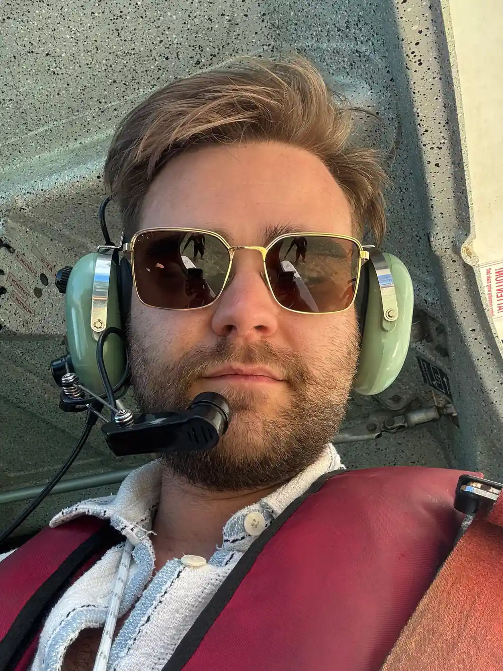 A passenger in sunglasses and headset in the cabin