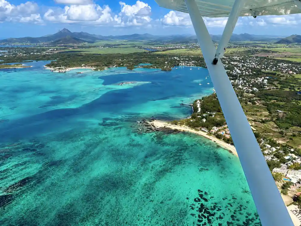 Past the wing strut to a green coastline and dark reef patches