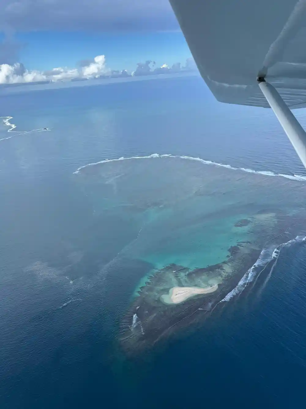 A reef flat and sandbank under bright water with deep blue behind