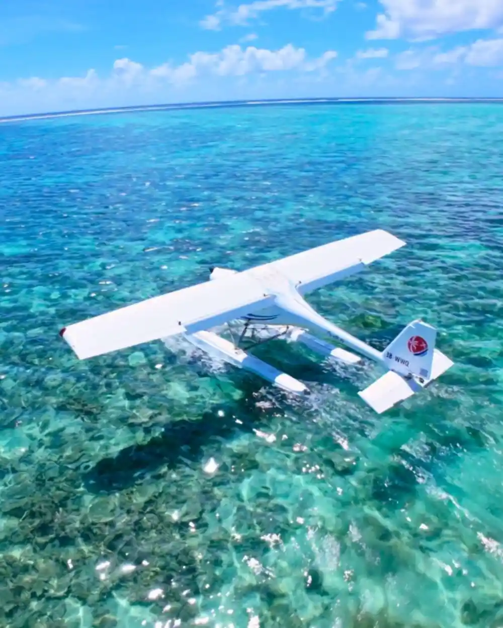 The seaplane from directly above, floats and shadow over clear shallow water