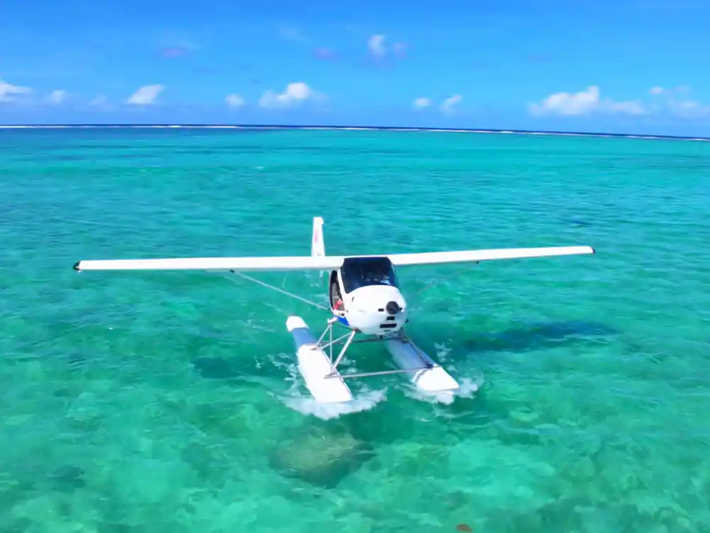 The seaplane on its floats crossing bright turquoise water, seen from above
