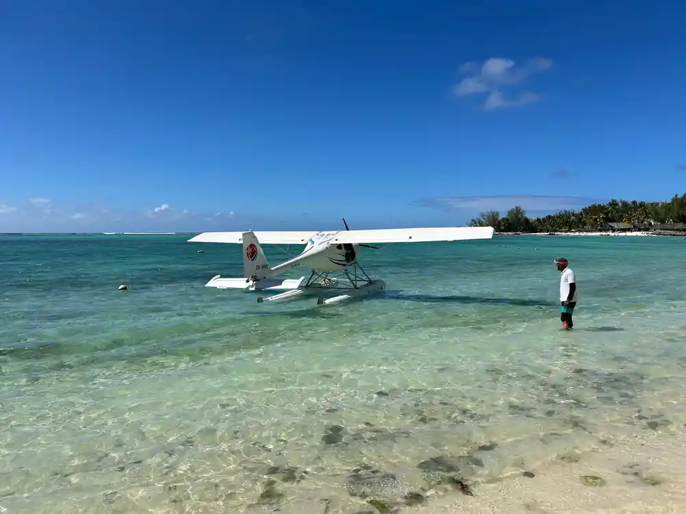 The seaplane moored in ankle-deep water with a man standing beside it