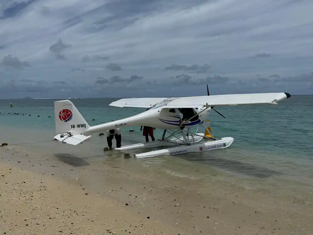 The seaplane on a sandbar with crew, under overcast sky