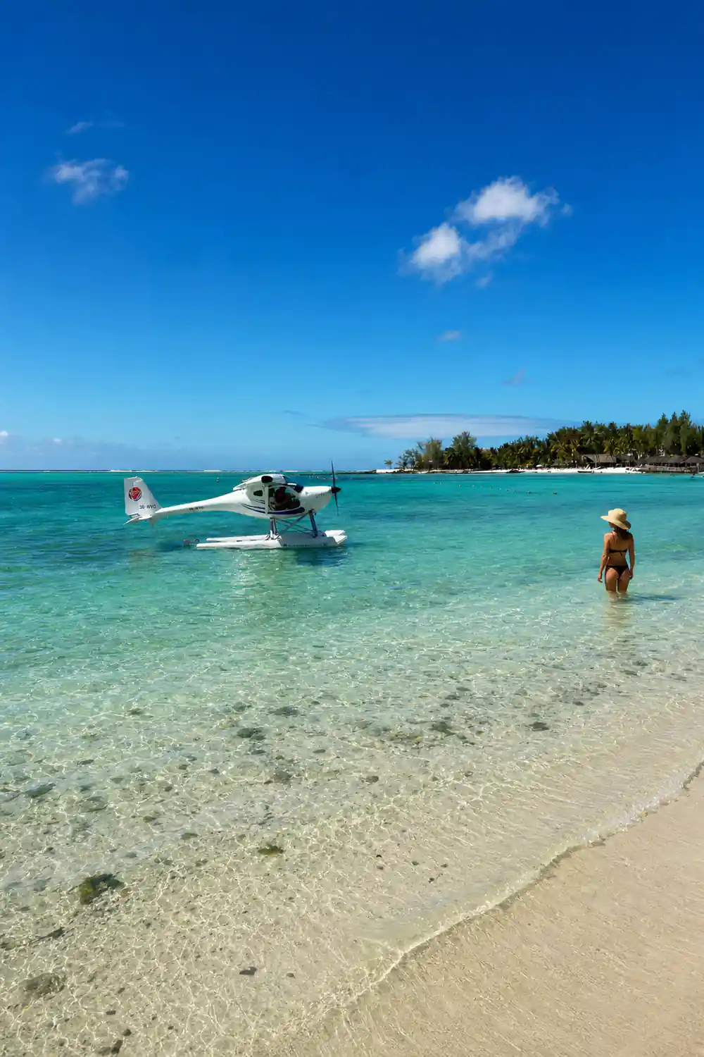 The seaplane taxiing near shore with a man wading out to it