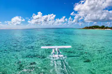 The seaplane taxiing towards the camera across bright turquoise shallows